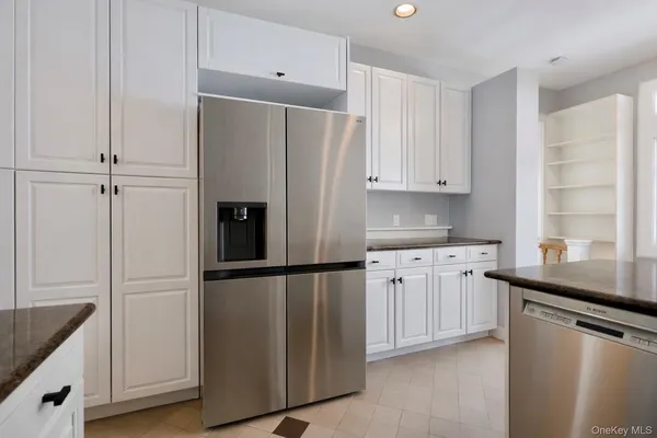 a kitchen with granite countertop stainless steel appliances a refrigerator a sink and cabinets