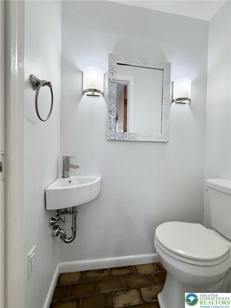 5540 Main Street Whitehall, PA 18052 - Photo 16 of 53 A compact and functional bathroom features a corner sink, toilet, and sconce lighting, all set against neutral walls.