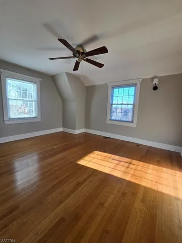 a view of empty room with wooden floor and fan