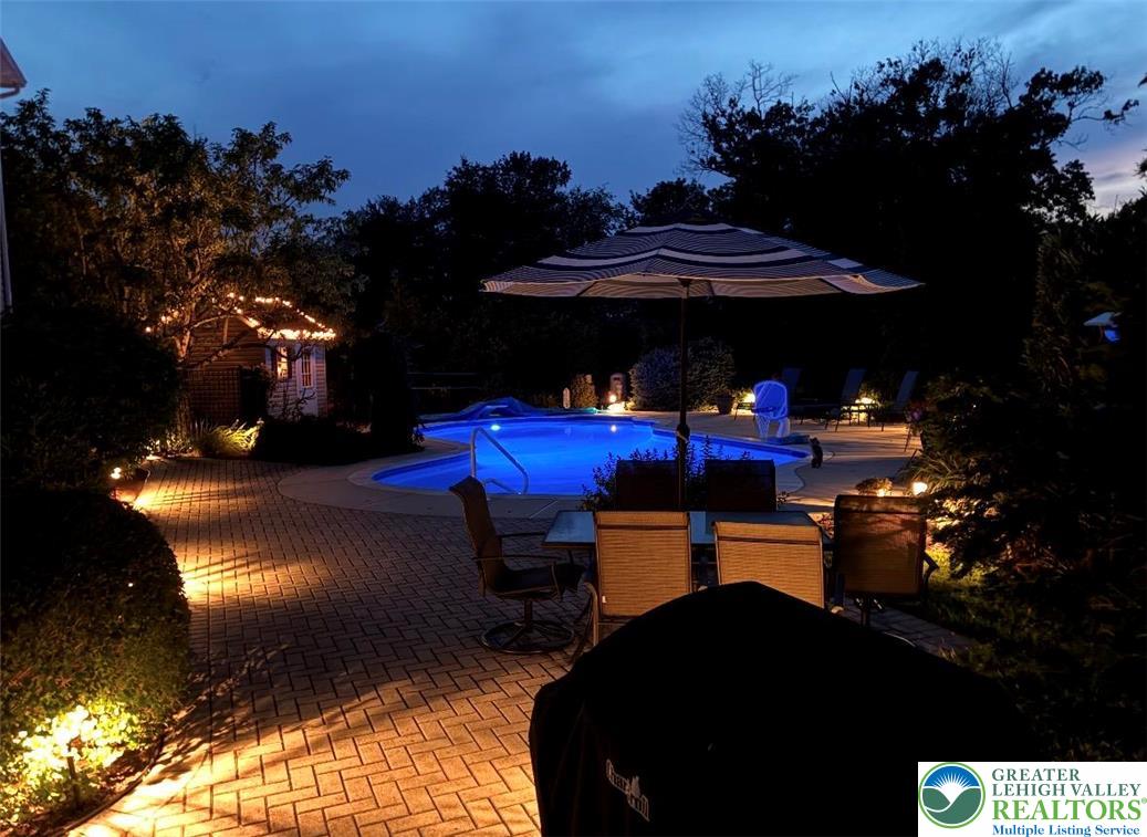 4059 Old Sentry Road Allentown, PA 18104 - Photo 35 of 39 An illuminated backyard oasis with a sparkling pool and cozy gathering spots, ideal for evening entertainment.