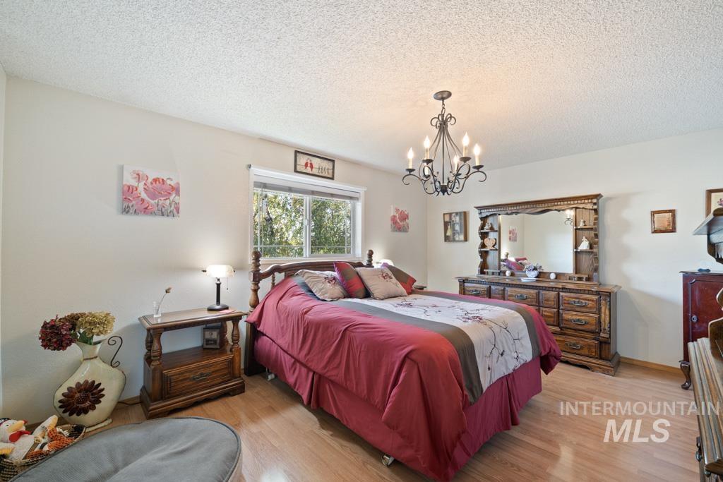 3828 15th Street Lewiston, ID 83501 - Photo 14 of 34 Bedroom with a textured ceiling, light wood-style flooring, and a chandelier