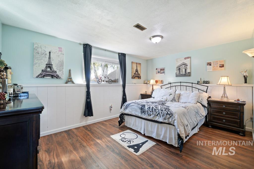 3828 15th Street Lewiston, ID 83501 - Photo 15 of 34 Bedroom featuring dark wood-type flooring, a wainscoted wall, a textured ceiling, and a decorative wall