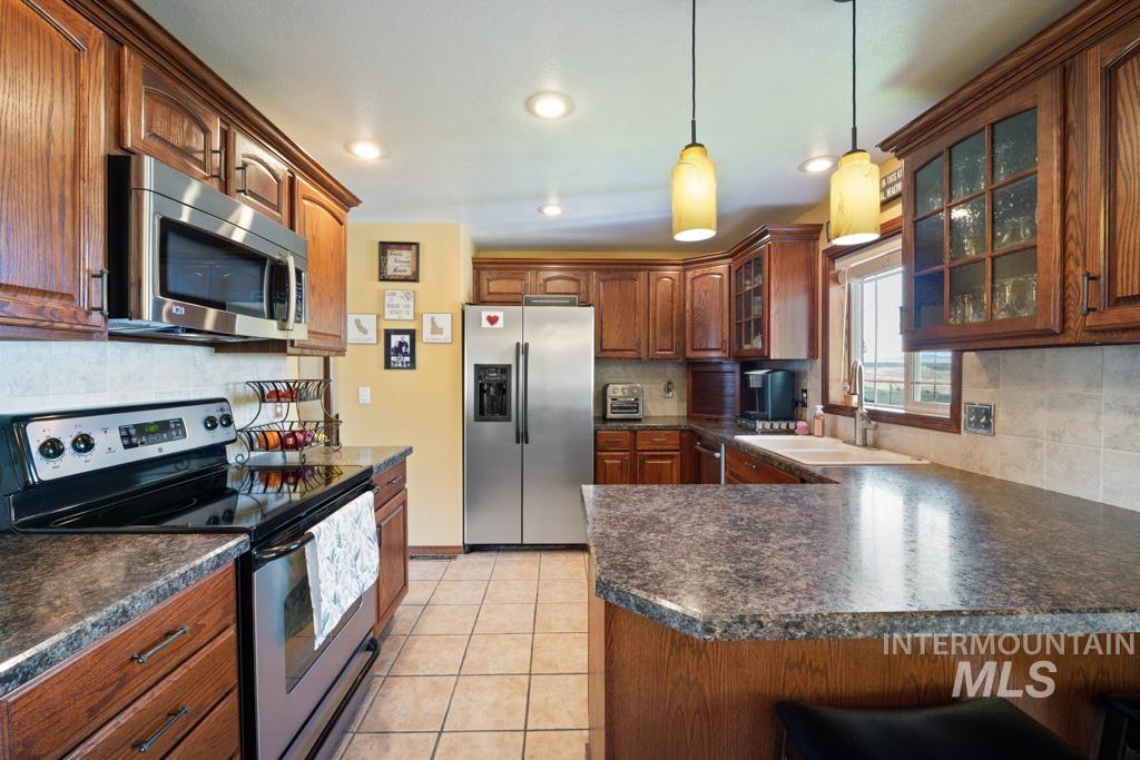 3828 15th Street Lewiston, ID 83501 - Photo 9 of 34 Kitchen featuring stainless steel appliances, glass insert cabinets, pendant lighting, light tile patterned floors, and dark countertops