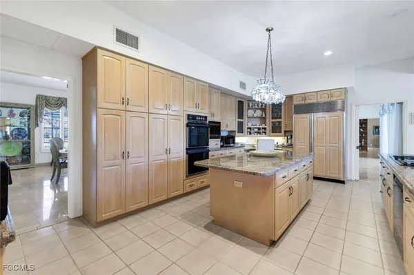 a kitchen with kitchen island granite countertop a refrigerator oven a sink dishwasher and a refrigerator