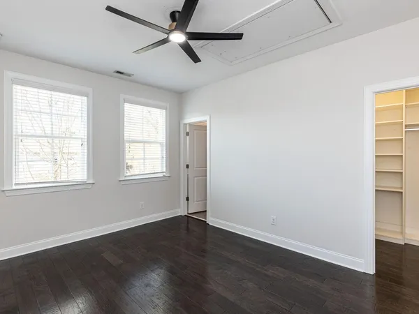 an empty room with wooden floor fan and windows