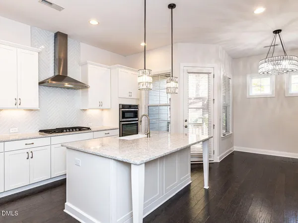 a kitchen with stainless steel appliances a sink a stove a refrigerator and wooden floor