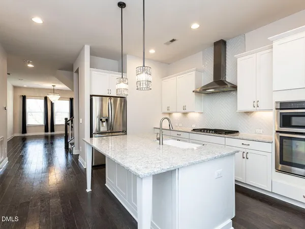a kitchen with stainless steel appliances granite countertop a sink a stove and a wooden floors