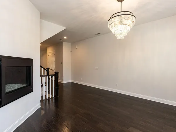 an empty room with wooden floor exposed radiator and way to kitchen