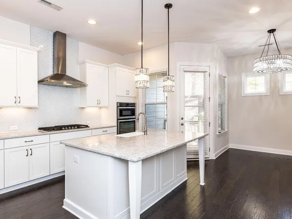 a kitchen with stainless steel appliances a sink a stove a refrigerator and wooden floor