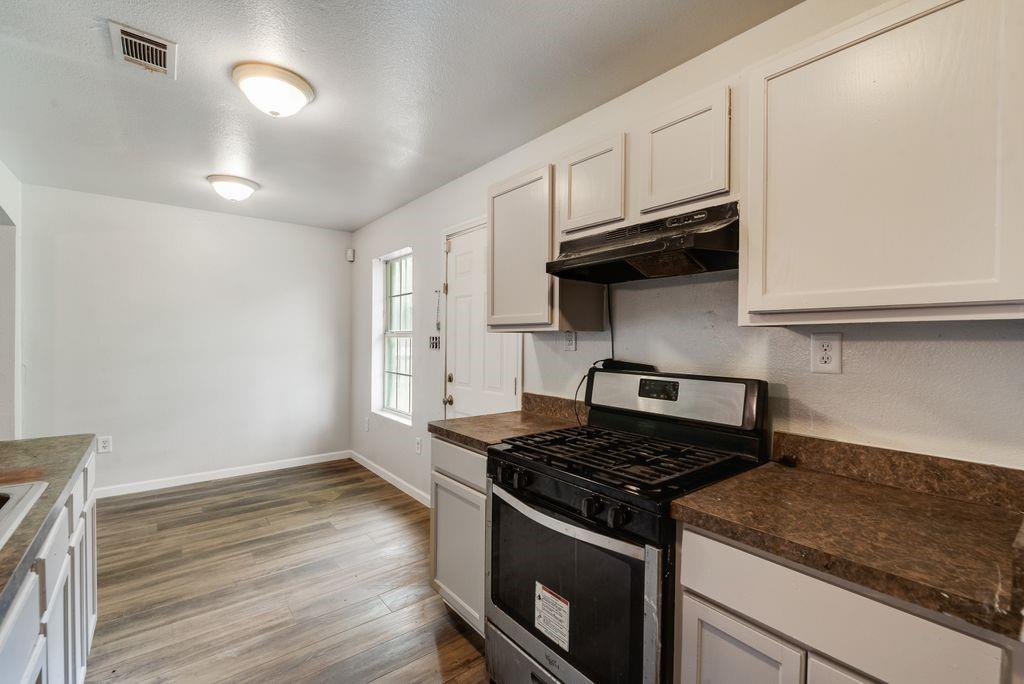 2526 Exeter Avenue Dallas, TX 75216 - Photo 13 of 19 Kitchen featuring a gas range, white cabinetry, and wood-finish flooring