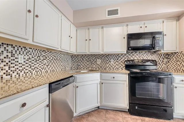 a kitchen with white cabinets granite counter tops and a stove