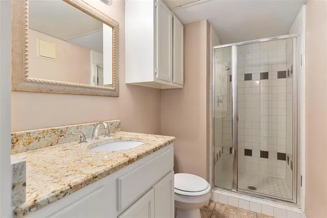 a bathroom with a granite countertop sink a toilet and shower