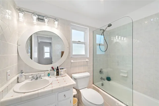 a bathroom with a sink a toilet and shower a mirror