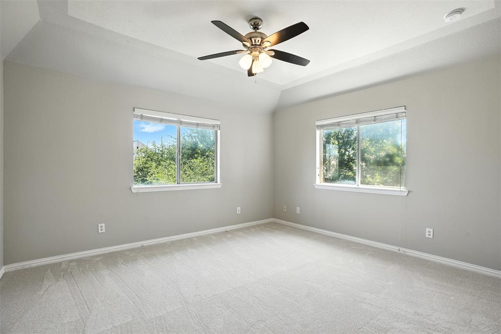 8220 Holliday Road Lantana, TX 76226 - Photo 33 of 40 Spacious room featuring a tray ceiling with a built-in ceiling fan, light gray wall paint, and plush carpeting