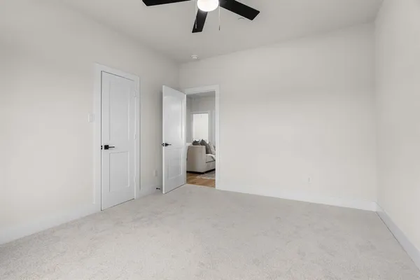 an empty room with a ceiling fan and carpet