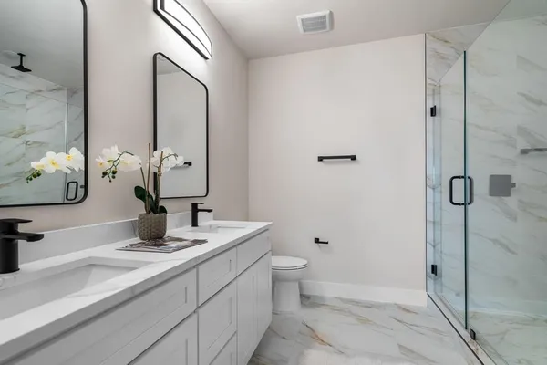 a bathroom with a double vanity sink toilet and shower