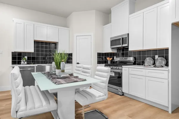 a kitchen with stainless steel appliances granite countertop a stove a sink dishwasher a dining table and chairs with wooden floor