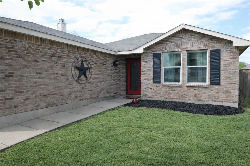 Doorway to property featuring a yard, a chimney, and brick siding