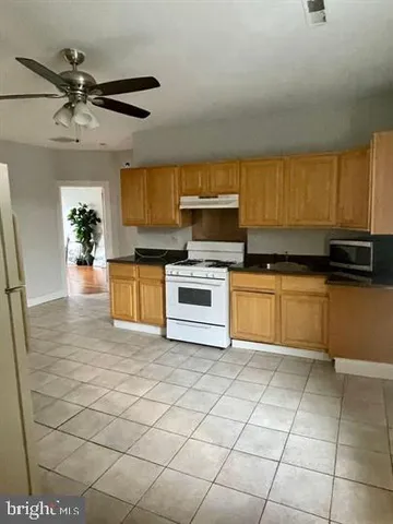 a kitchen with stainless steel appliances granite countertop a sink a stove top oven a chimney a counter space and cabinets