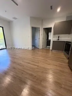 a view of a kitchen with kitchen island a sink wooden floor and a counter top space