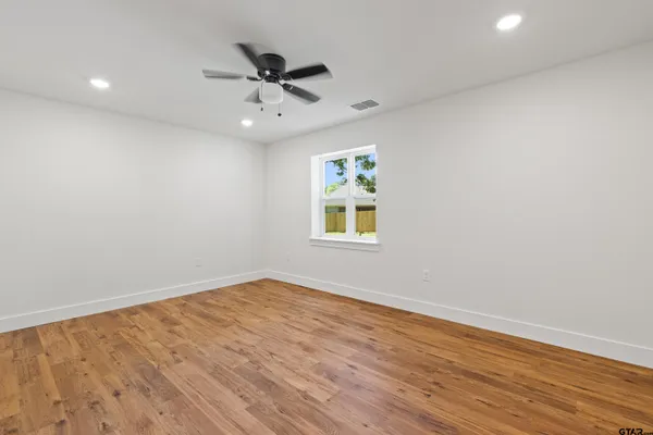 a view of an empty room with a window and wooden floor