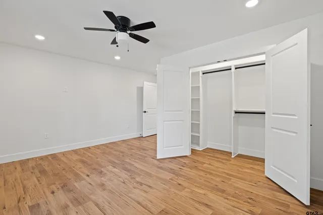 a view of an empty room with wooden floor and a kitchen