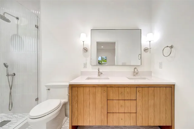 a bathroom with a toilet a sink a mirror and shower