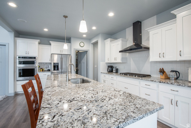 262 North Santa Fe Drive Mapleton, UT 84664 - Photo 13 of 28 Kitchen featuring a breakfast bar, white cabinets, light stone counters, stainless steel appliances, and decorative backsplash