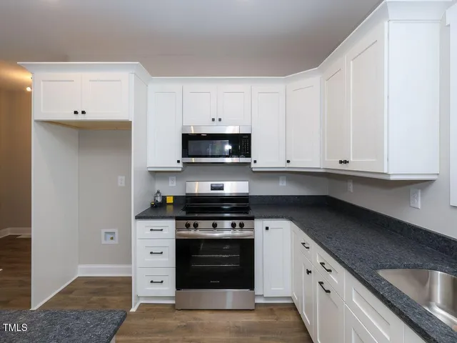 a kitchen with granite countertop white cabinets and stainless steel appliances