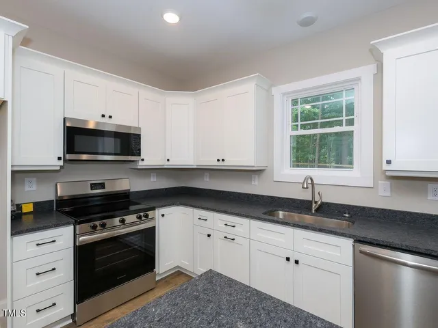 a kitchen with granite countertop white cabinets and black appliances