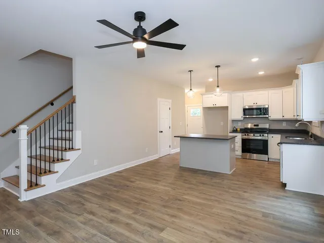 a view of kitchen with stainless steel appliances kitchen island wooden floor granite counter space and a sink