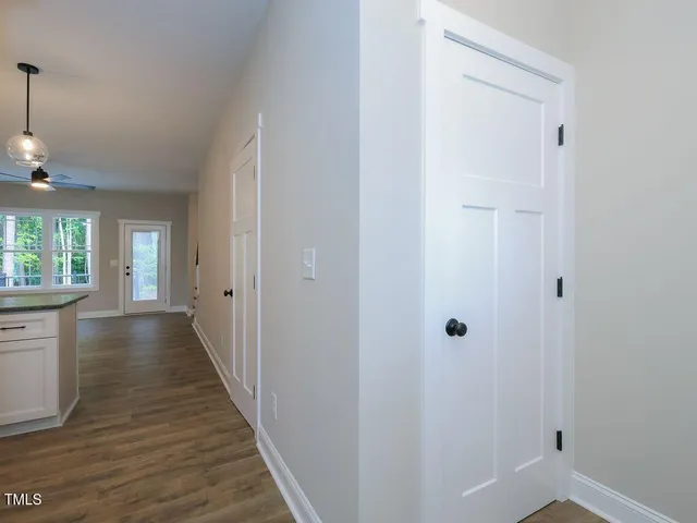 a view of a hallway with wooden floor and a bathroom