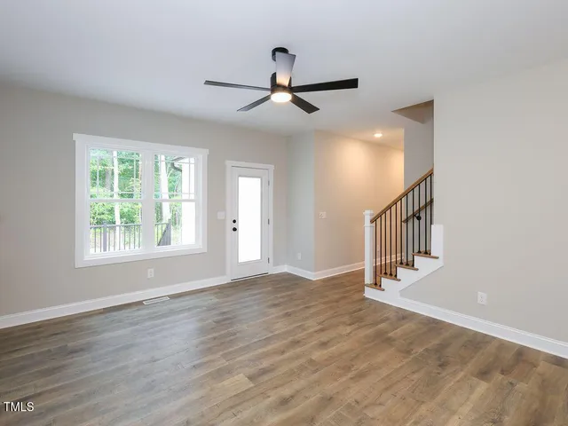 an empty room with wooden floor fan and windows