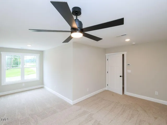 an empty room with windows and fan