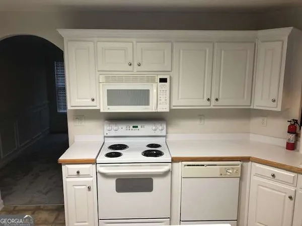 a kitchen with white cabinets and white appliances