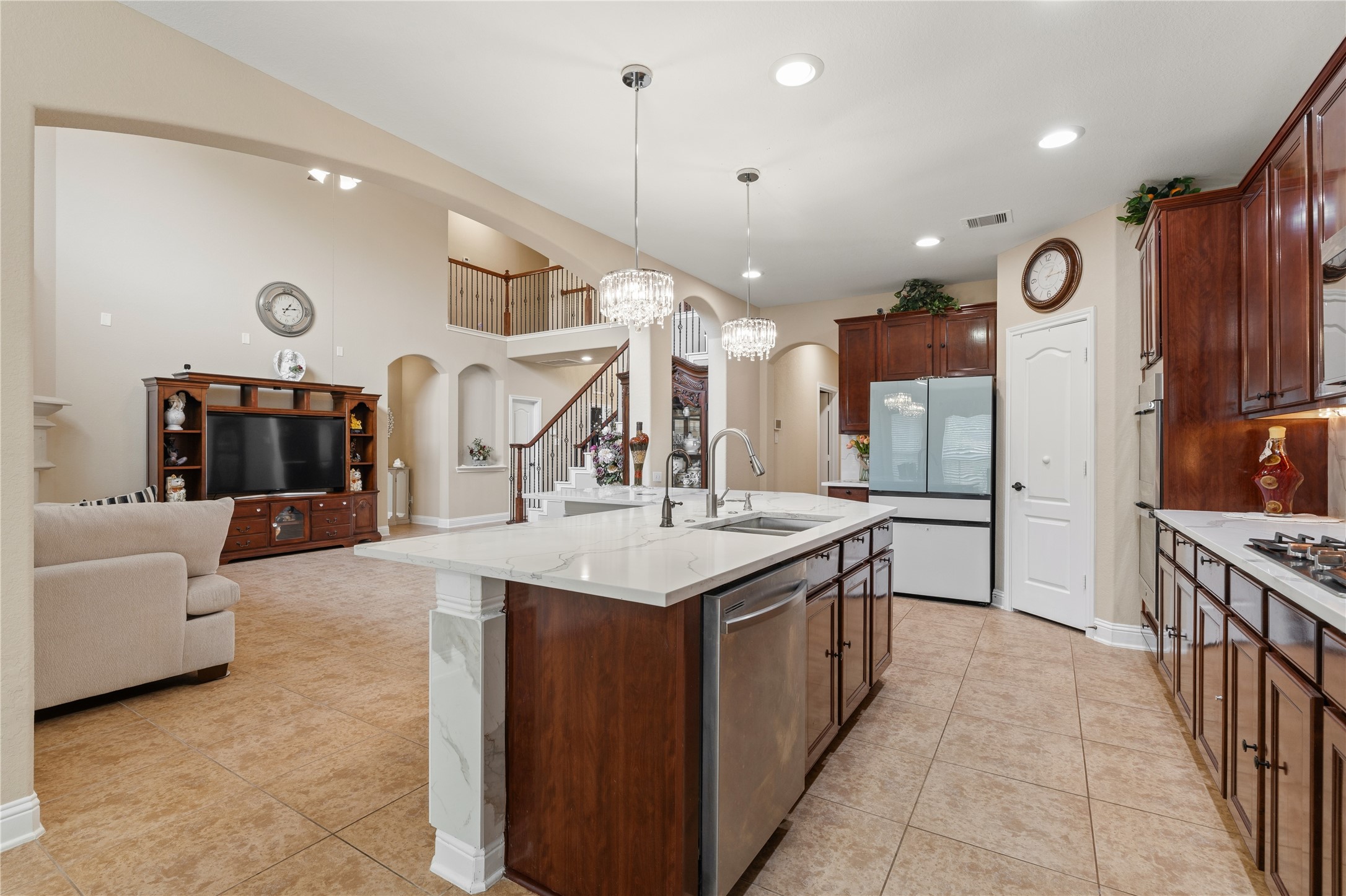5802 Layton Meadows Lane Spring, TX 77379 - Photo 14 of 42 Kitchen open-concept view. Island in the foreground, living room and staircase visible in the background. This photo tells the whole open-concept story — kitchen flows to living room, staircase, and second floor balcony all in one frame.