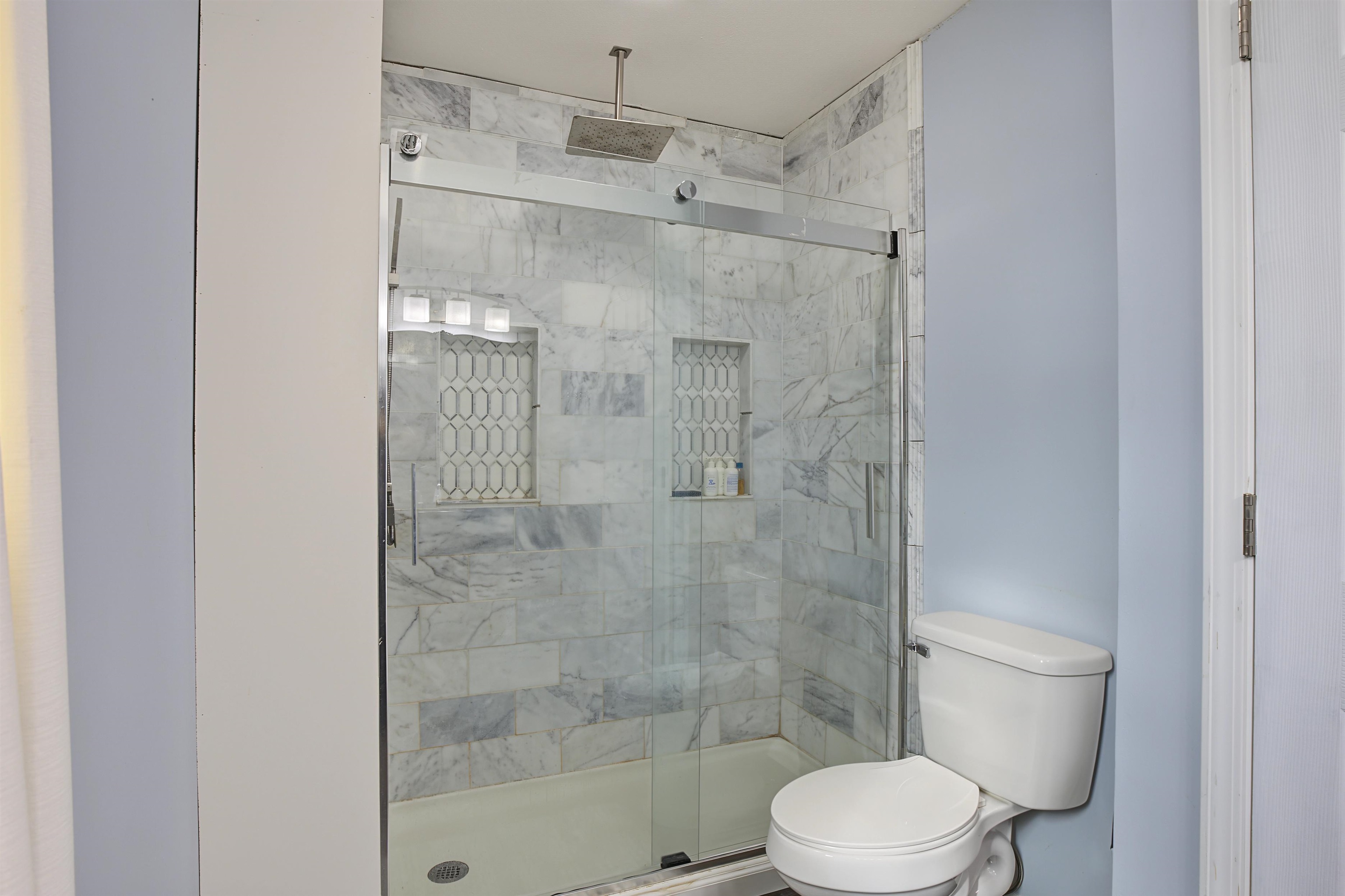 246 Cherryville Road Bells, TN 38006 - Photo 26 of 31 Glass-enclosed shower with a rainfall showerhead, tiled walls, and two recessed shelves with decorative mosaic tile