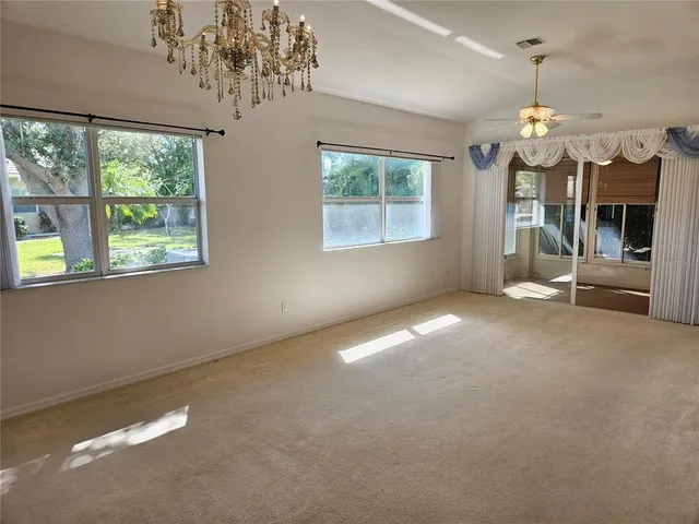 a view of a livingroom with a chandelier fan and windows