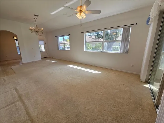 en empty room with windows and ceiling fan