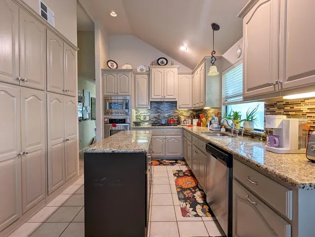a kitchen with stainless steel appliances granite countertop a refrigerator a sink dishwasher and white cabinets with wooden floor