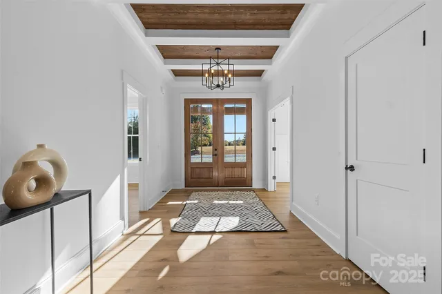 a view of a hallway with wooden floor and a chandelier
