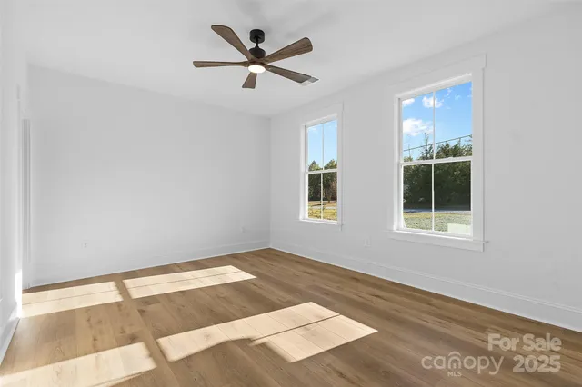 a view of a big room with wooden floor and windows
