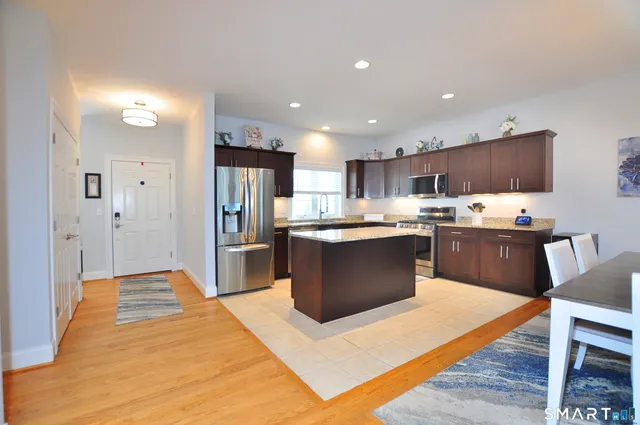 a kitchen with stainless steel appliances kitchen island granite countertop a refrigerator and a stove top oven