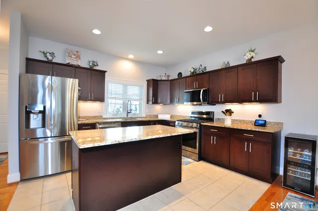 a kitchen with stainless steel appliances granite countertop a refrigerator a sink a stove a microwave and wooden cabinets