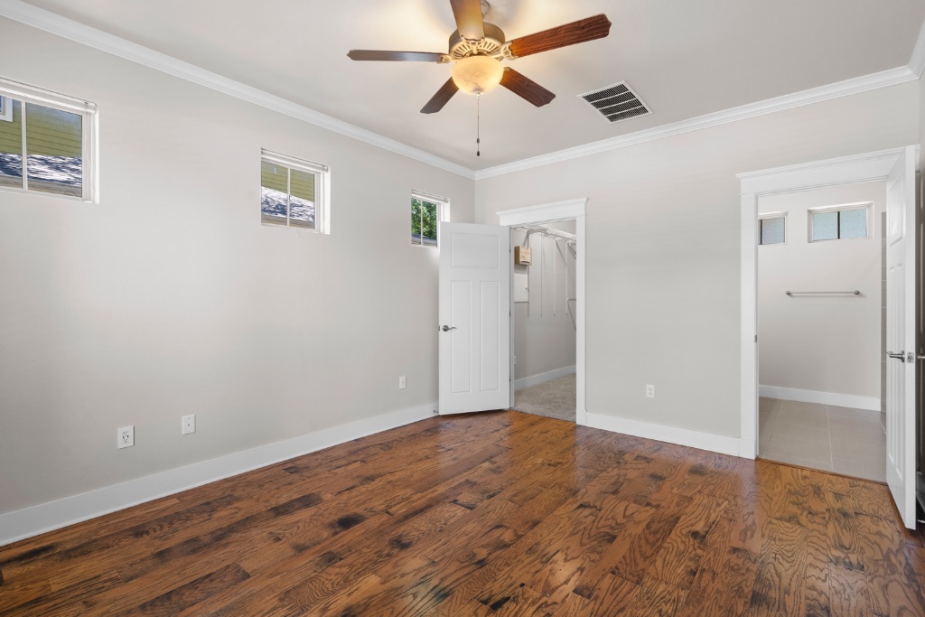 11229 Avery Station Loop, Unit 36 Austin, TX 78717 - Photo 14 of 37 Unfurnished bedroom featuring dark wood-style flooring, a walk in closet, crown molding, and a ceiling fan