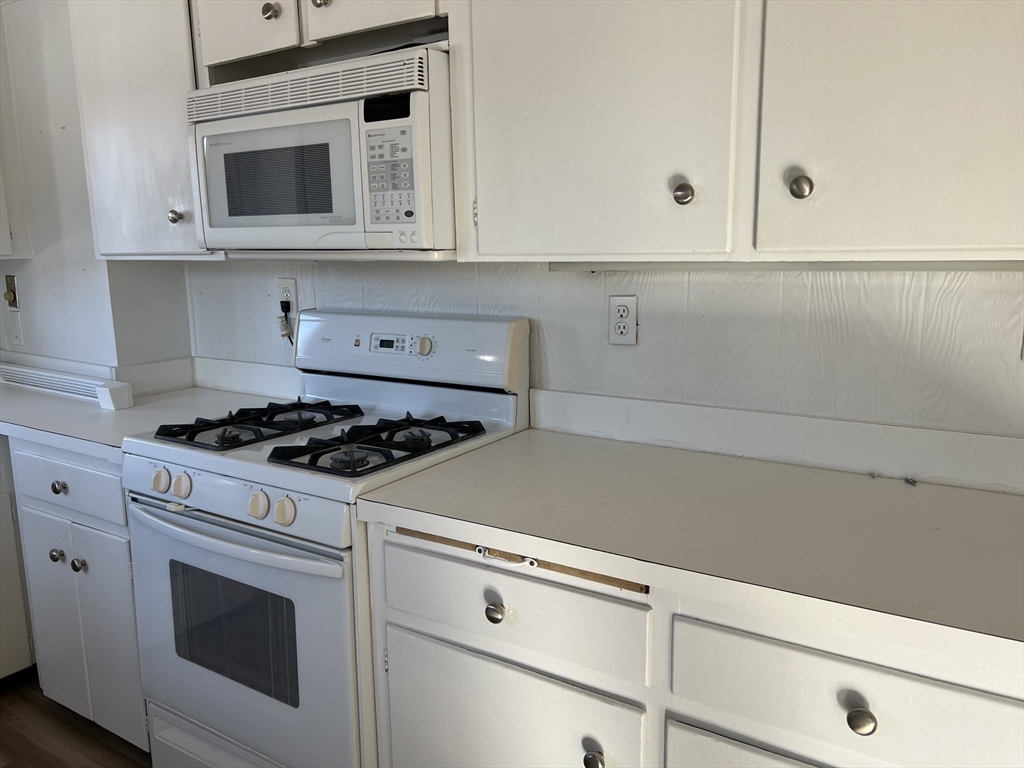 175 Spring Street, Unit 1 Hull, MA 02045 - Photo 6 of 15 a kitchen with white cabinets and appliances