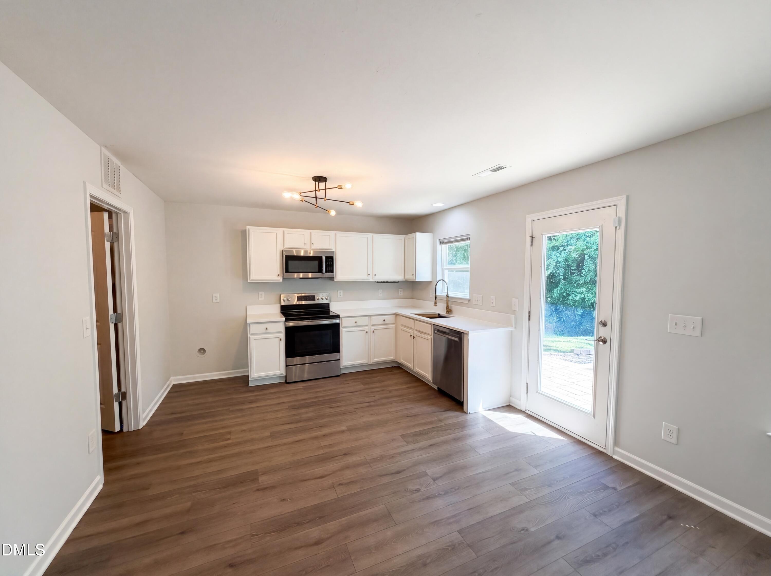4716 Queen Pierrette Street Raleigh, NC 27610 - Photo 2 of 15 a large kitchen with white cabinets and wooden floor