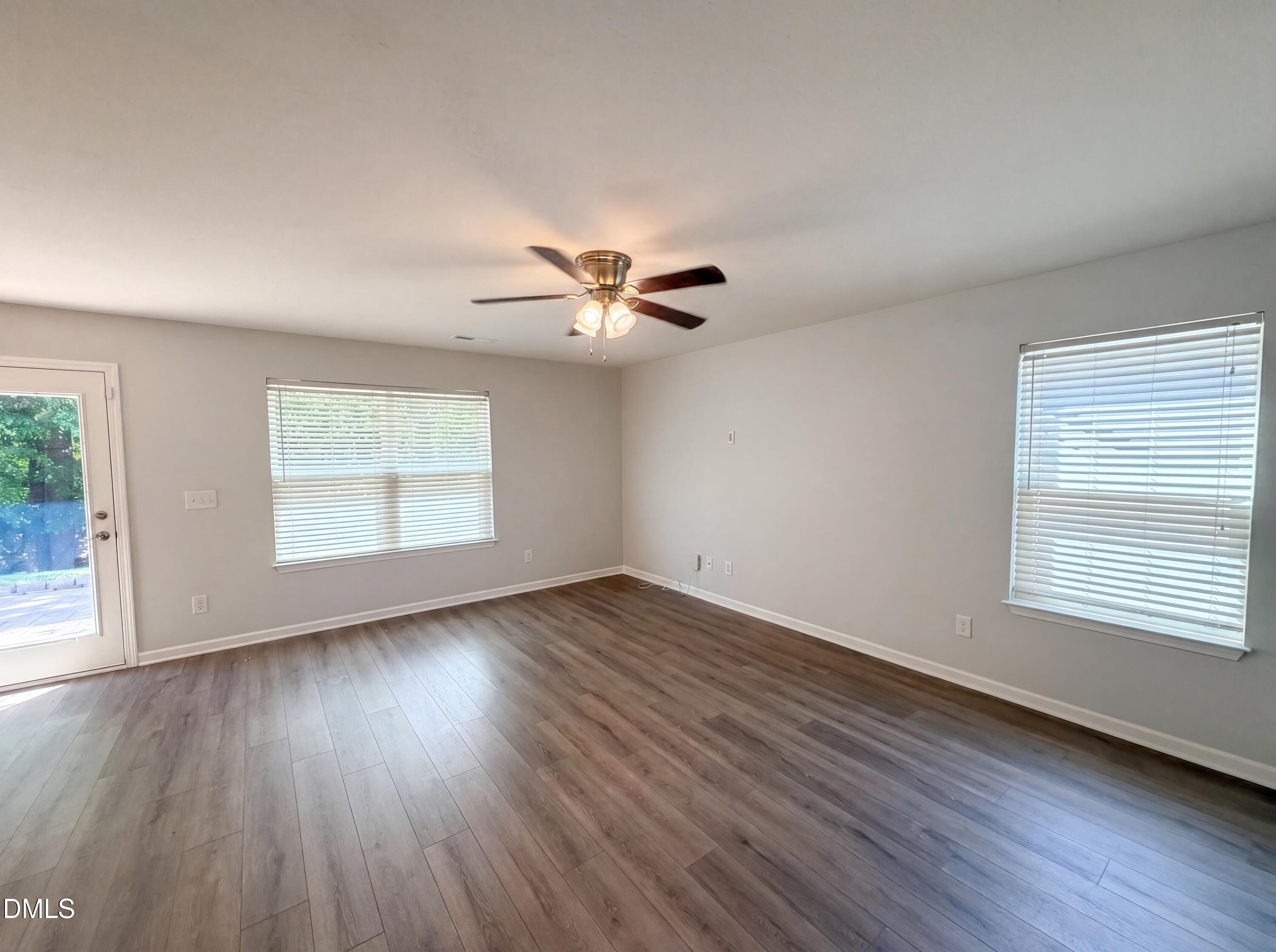 4716 Queen Pierrette Street Raleigh, NC 27610 - Photo 3 of 15 an empty room with wooden floor chandelier fan and windows
