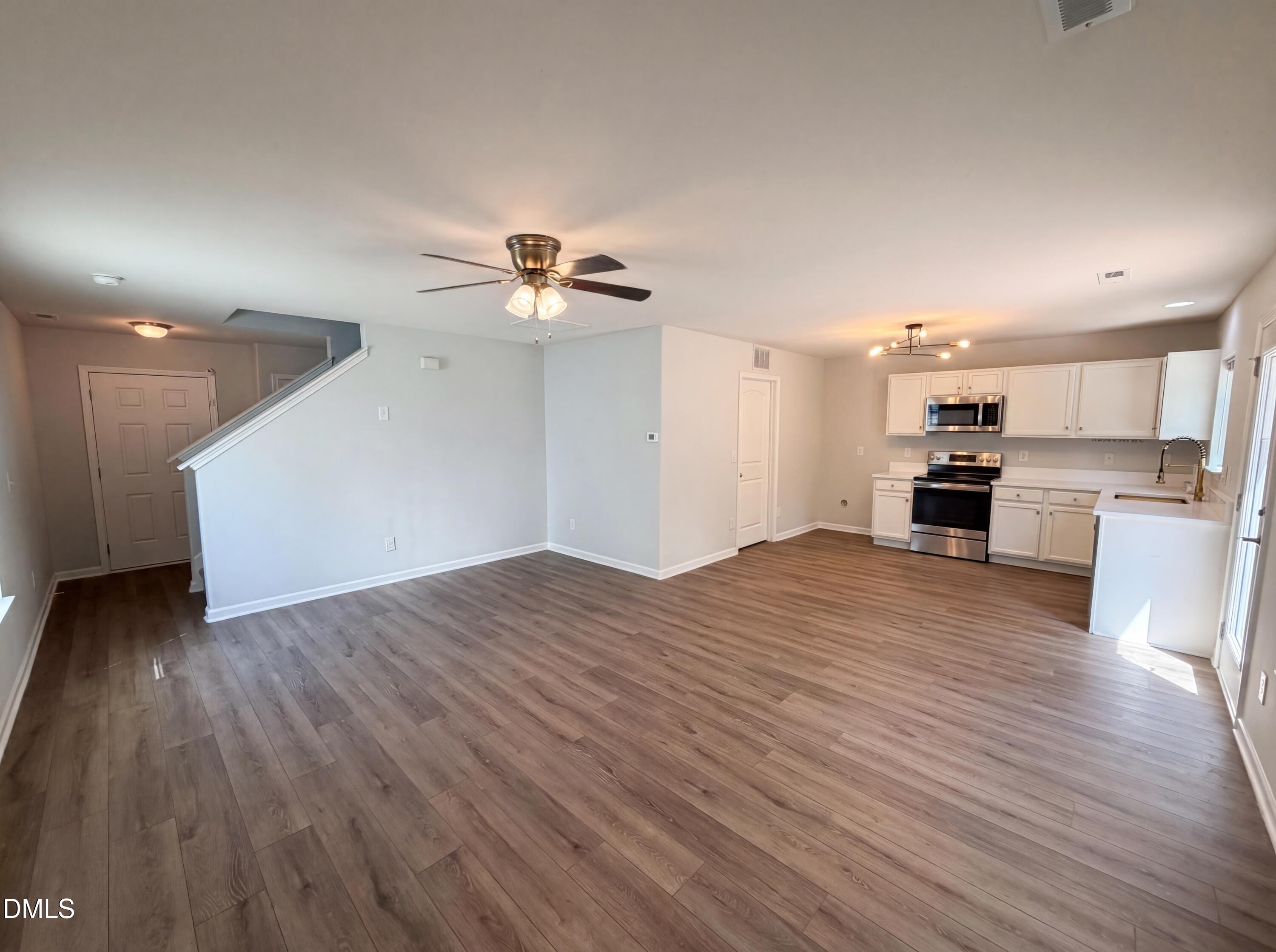 4716 Queen Pierrette Street Raleigh, NC 27610 - Photo 8 of 15 a view of empty room with wooden floor and kitchen view