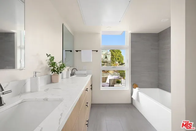 a bathroom with a granite countertop sink a bathtub and a window